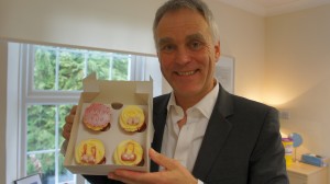 Consultant plastic surgeon Mr Adrian Richards holding cupcakes